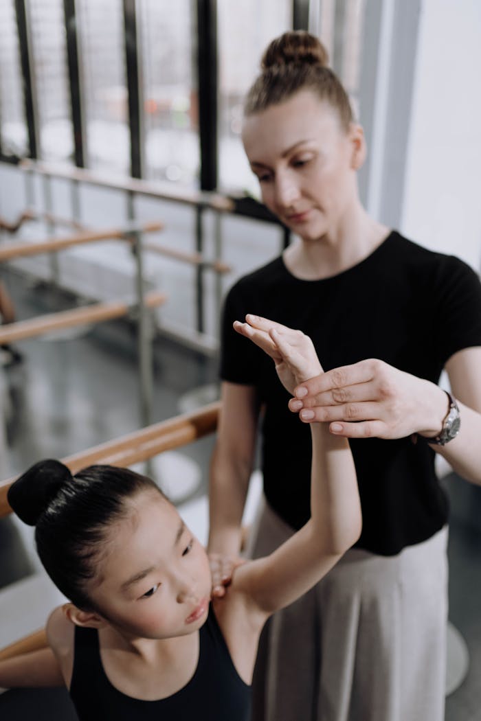 Ballet teacher guiding young girl in dance studio, focused lesson.